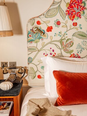 A bedroom with a floral headboard, a vintage telephone, and a red pillow. - The Leinster (Dublin)