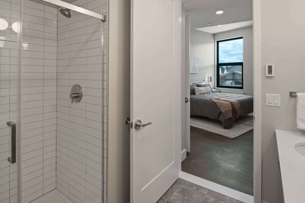 A modern bathroom with a glass shower enclosure, a visible toilet, and a sink. - Dog Friendly Top Floor Condo w/Rooftop Hot tub (Sandpoint)