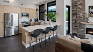 A modern kitchen with a central island, stainless steel appliances, and a dining area with bar stools.