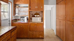 A kitchen with wooden cabinets, a microwave, and a tiled backsplash.