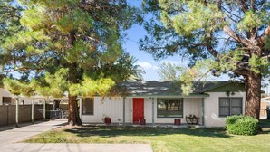 A single-story house with a red door, a covered porch, and a small front yard.