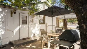 A covered patio with a table, chairs, and a grill.