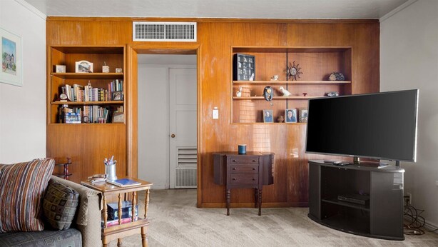 A living room with a wooden bookshelf, a television, and a sofa.