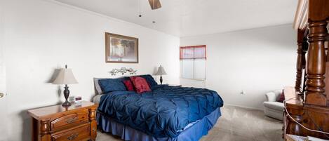 A bedroom with a bed, nightstand, dresser, ceiling fan, and a window with blinds.