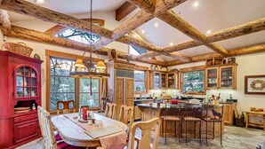 Una cucina rustica con travi in legno, un'area pranzo con pavimento in pietra e un armadietto rosso con vetrate.