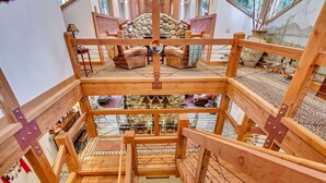 Una struttura in legno a più livelli con una scala centrale, circondata da diverse zone relax e elementi decorativi.