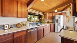 A modern kitchen with wooden cabinets, stainless steel appliances, and a large island.