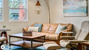 Ein gemütliches Wohnzimmer mit Ledersofa, Couchtisch aus Holz und moderner Stehlampe.