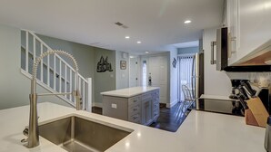 A modern kitchen with a stainless steel sink, white countertops, and a built-in island with drawers. - Updated New Luxury Vacation Condo w New Kitchen Bikes & Beach Gear included (Hilton Head Island)