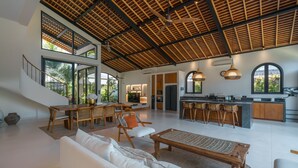 A spacious living area with a high ceiling, a dining area, and a kitchen with a large island. - Casa Donilo  (Canggu)
