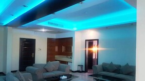 A modern living room with two sofas, a coffee table, and a TV. There is a wooden cabinet and a door in the background. - Panorama Hotel and Spa (Manama)