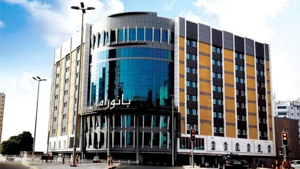 A modern building with a curved glass facade, multiple floors, and a prominent entrance with signage. - Panorama Hotel and Spa (Manama)