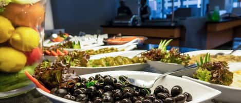 A buffet with various dishes including olives, salads, and other prepared foods.