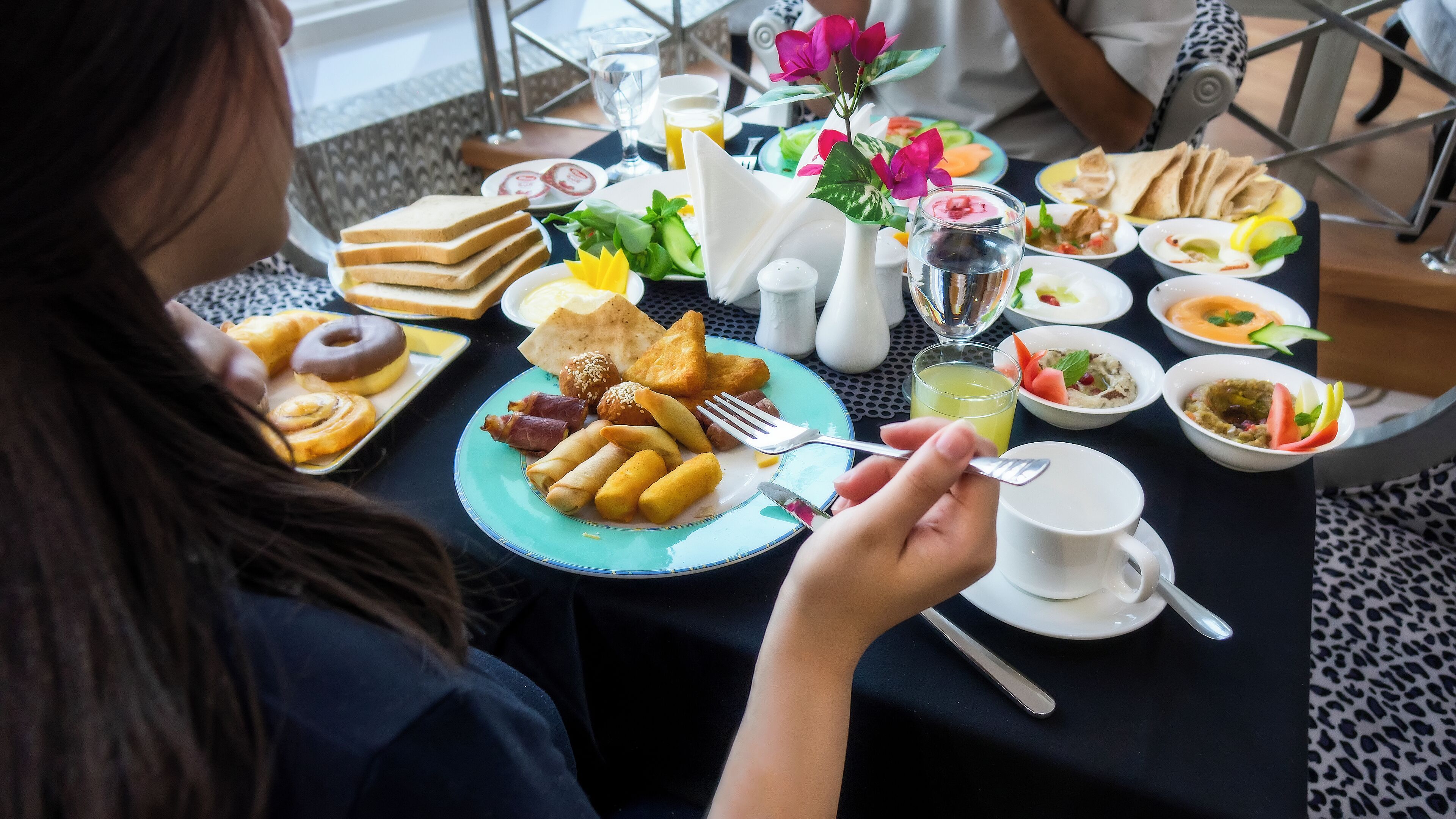 A dining table with various dishes, including bread, pastries, and a cup of tea.