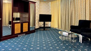 A hotel room with a large mirror, a black sofa, a glass coffee table, and a television. - Panorama Hotel and Spa (Manama)