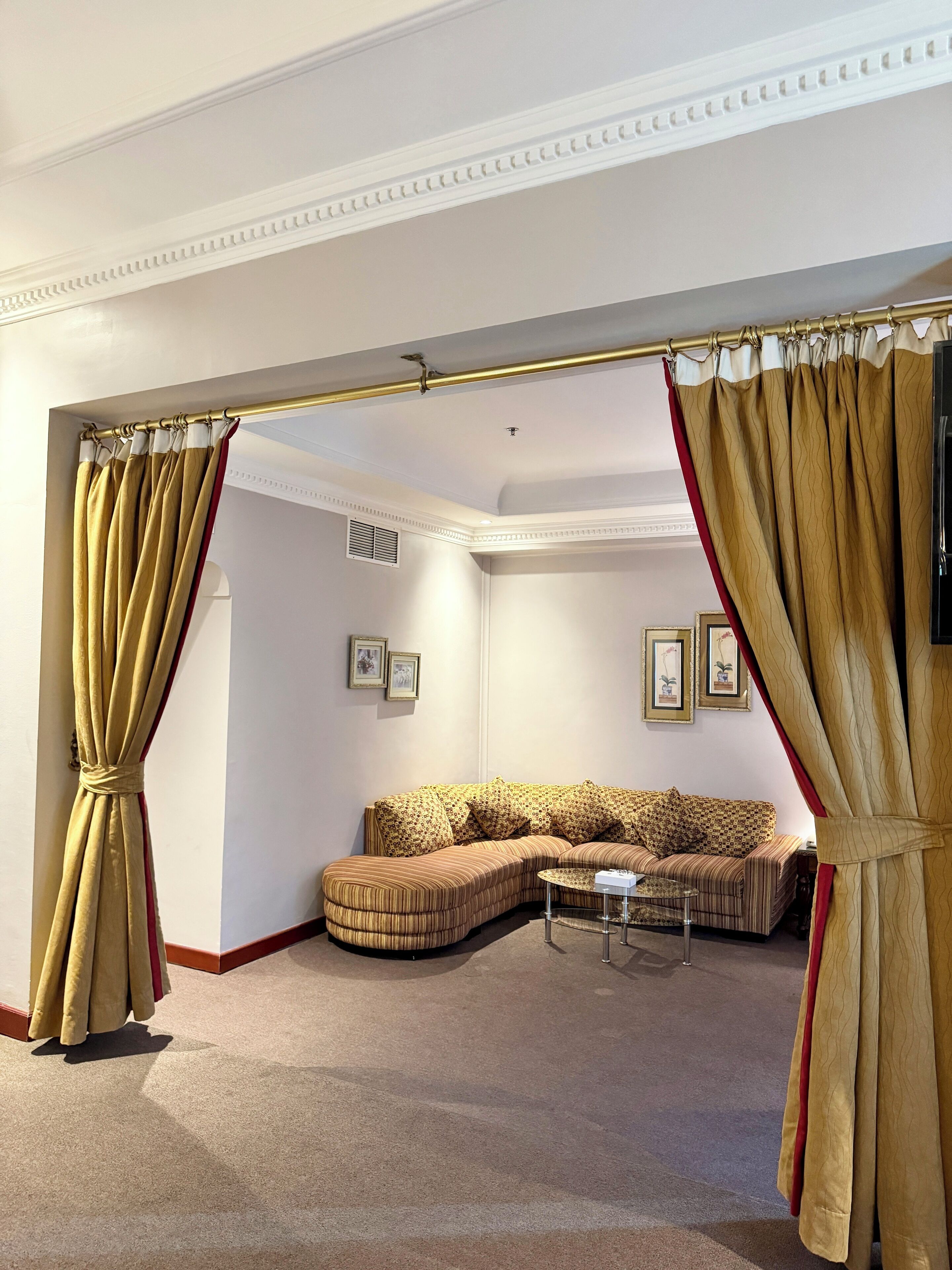 A living room with a sectional sofa, a coffee table, and a view through a doorway with curtains.