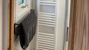 Un baño con ventana, un perchero y un radiador blanco.