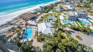 An aerial view of a coastal resort with a large pool, multiple buildings, and a beach. - Beachfront ~ Private Balcony ~ Golf Cart (Miramar Beach)