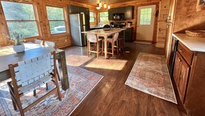 A spacious kitchen with wooden cabinets, a central island, and a dining area with a table and chairs. - Private & secluded beach front on Lake Huron! (Cheboygan)
