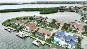 An aerial view of a waterfront residential area with houses, docks, and a marina. - Direct Boating Access | Waterfront Home w/ Pool/Spa (Marco Island)