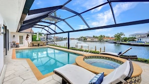 A swimming pool with a hot tub, lounge chairs, and a view of the waterway. - Direct Boating Access | Waterfront Home w/ Pool/Spa (Marco Island)