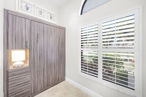 A room with a wardrobe, a window with blinds, and a framed picture above the window. - Direct Boating Access | Waterfront Home w/ Pool/Spa (Marco Island)