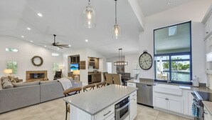 A modern kitchen with white cabinetry, a large island, and a view of the outdoors. - Direct Boating Access | Waterfront Home w/ Pool/Spa (Marco Island)