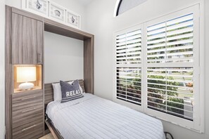 A bedroom with a bed, a nightstand, a lamp, a window with blinds, and a built-in wardrobe. - Direct Boating Access | Waterfront Home w/ Pool/Spa (Marco Island)