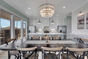 Una cocina moderna con una isla central, iluminación colgante y vistas amplias a través de grandes ventanales.