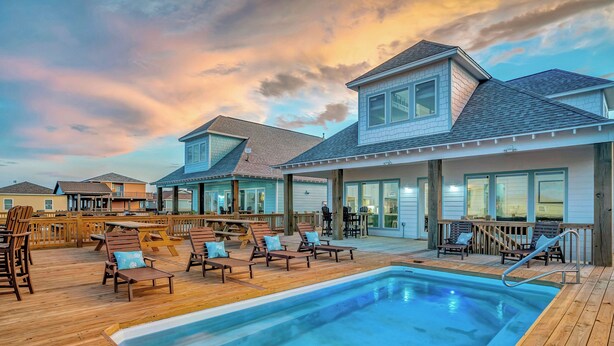A pool area with lounge chairs and a wooden deck. - Sunny & 75: 5  BR, 5.5  BA House in Crystal Beach, Sleeps 26 (Bolivar Peninsula)