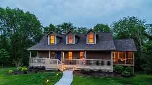 A two-story house with a porch, a covered deck, and a pathway leading to the entrance. - Beautiful Bluebirds and Star Studded Skies Surround! 
EV Charge / Pet Friendly! (Galena Territory)