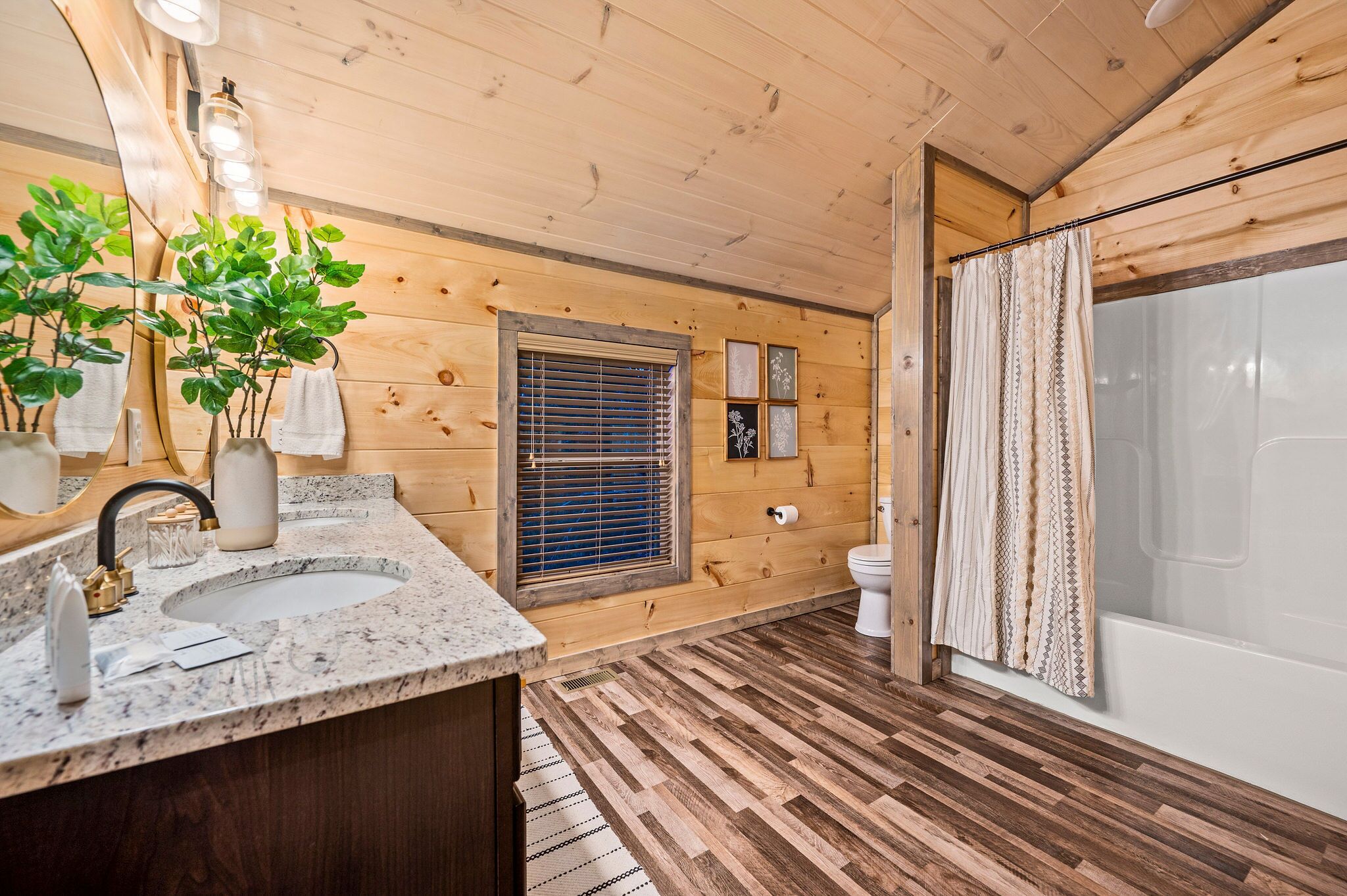 A wooden cabin bathroom with a sink, toilet, and shower.