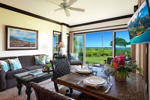A dining area with a table set for four, a sofa, and a chair. - G106 - Stunning Ground-Floor Oceanfront Suite with AC Steps to the Water! (kapaa)