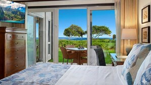 Un dormitorio con cama, cómoda, mesa y sillas, y vista al océano.