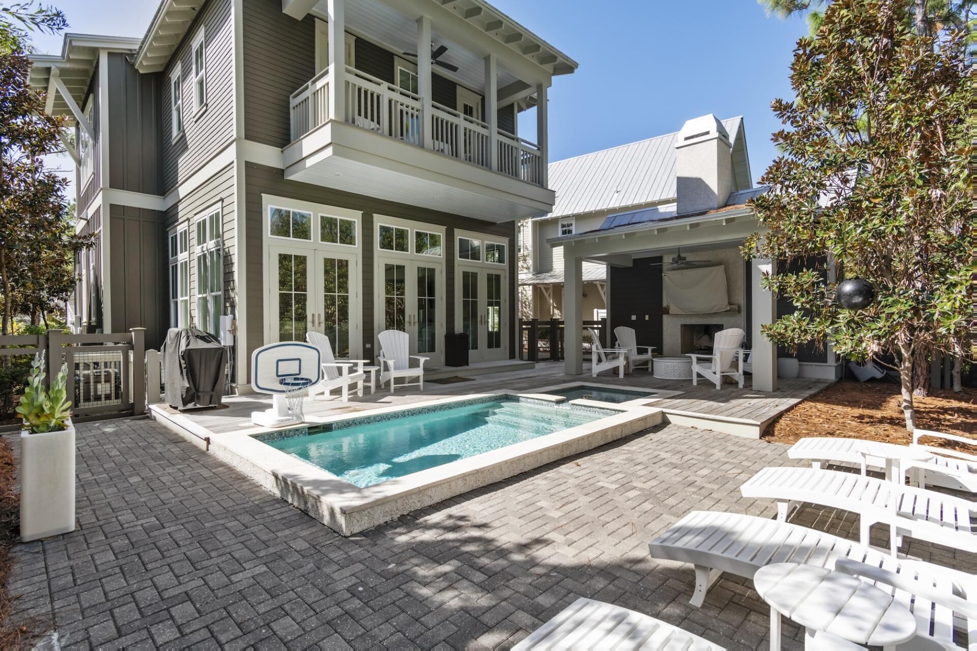 A two-story house with a swimming pool, outdoor seating, and a covered patio area.