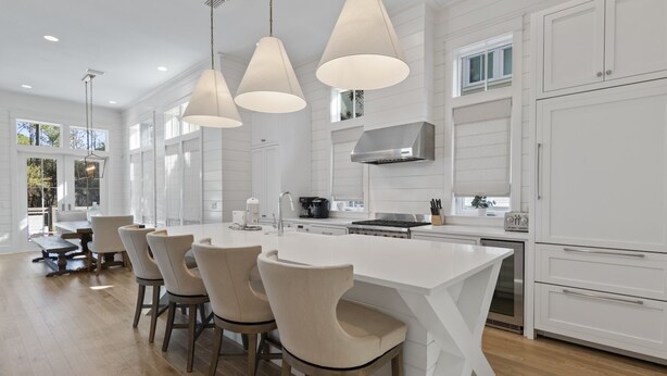 A modern kitchen with a large island, white cabinetry, and pendant lighting.