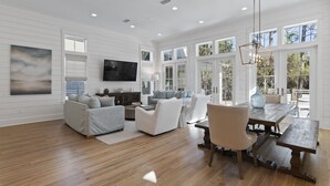 A spacious living room with a large TV, comfortable seating, and a dining area with a wooden table and chairs.