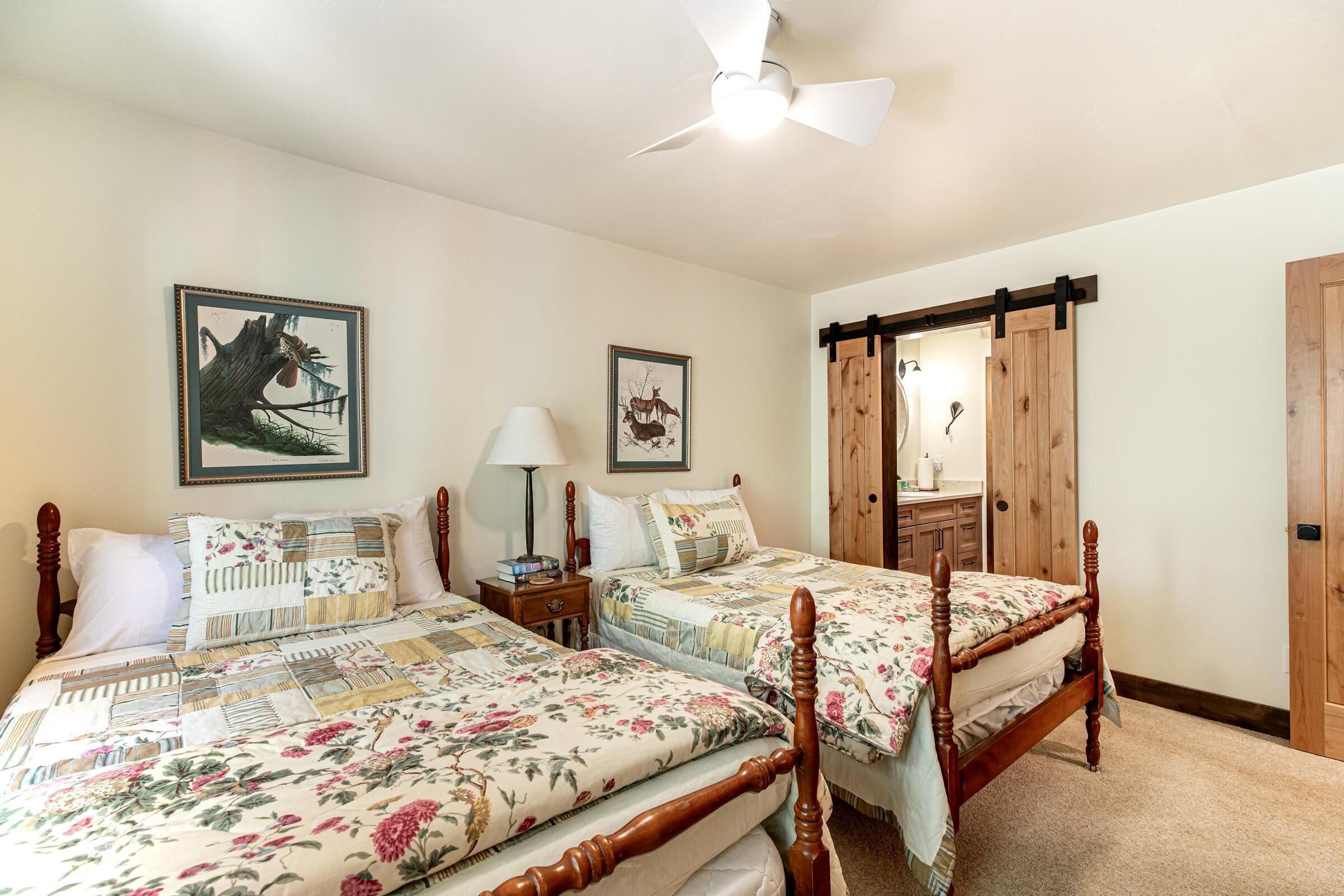 A bedroom with two wooden beds, a ceiling fan, and a wooden wardrobe.
