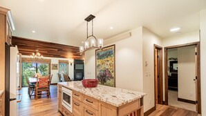 A kitchen with wooden cabinets, a granite countertop, and a hanging light fixture.