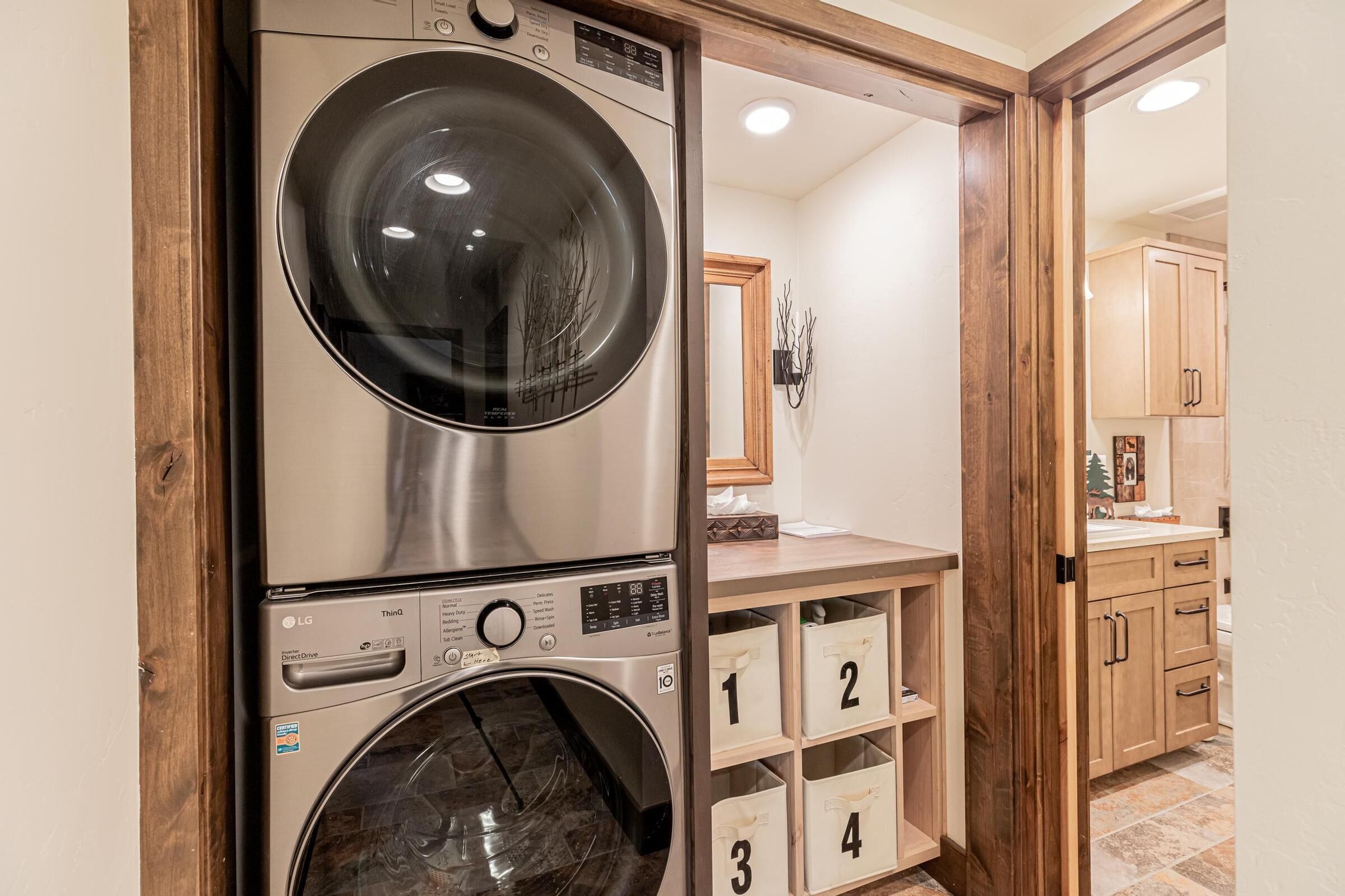 A laundry room with stacked washers and dryers, wooden cabinets, and numbered storage bins.