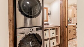 A laundry room with stacked washers and dryers, wooden cabinets, and numbered storage bins.