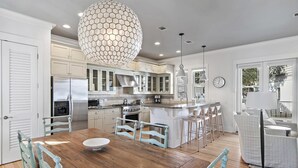 Una cocina moderna con armarios blancos, una isla central y una lámpara colgante.