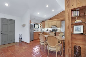 A kitchen with wooden cabinets, a dining table with chairs, and a microwave.
