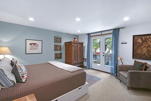 A bedroom with a bed, a wooden cabinet, a couch, and a door leading to a balcony.