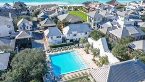 An aerial view of a coastal residential area with a swimming pool surrounded by houses.