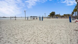 A sandy beach with a volleyball net, a pavilion, and a flagpole.