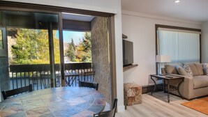A modern living room with a stone table, a sofa, and a TV. - Newly remodeled condo just steps from the gondola, hot tub, sleeps 4! (Vail)