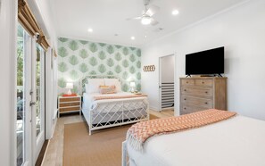 Un dormitorio con cama, mesitas de noche, cómoda, televisor y pared con diseño.