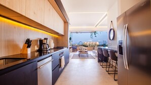 Une cuisine moderne avec des meubles en bois, un réfrigérateur en acier inoxydable et un coin bar équipé de tabourets.
