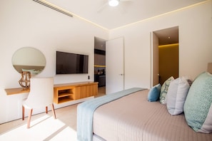 A modern bedroom with a bed, a TV, a desk, and a chair. - Soho PV • 2 Workspaces, Pool, Gym & Rooftop Bar (Puerto Vallarta)